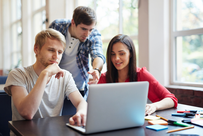 studenci siedzą w auli przed laptopem